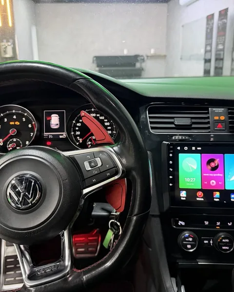 Painel de um Golf GTI: volante de couro com os comandos originais, instrumentos de fábrica intactos e a multimídia nova instalada e ligada ao lado.