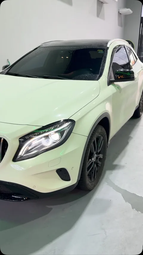 Mercedes-Benz GLA branca dentro da Evotek, com a iluminação verde da loja refletindo no farol e no retrovisor.